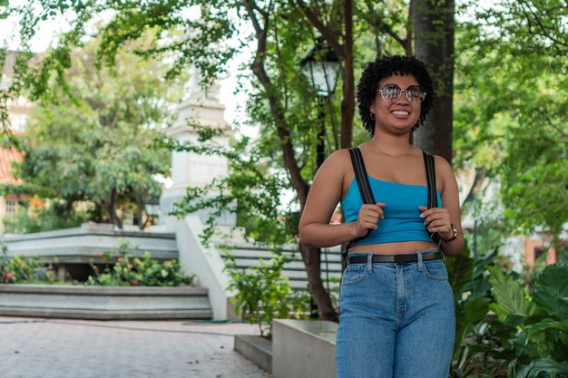 Mujer con peinado afro sonriendo en un parque urbano