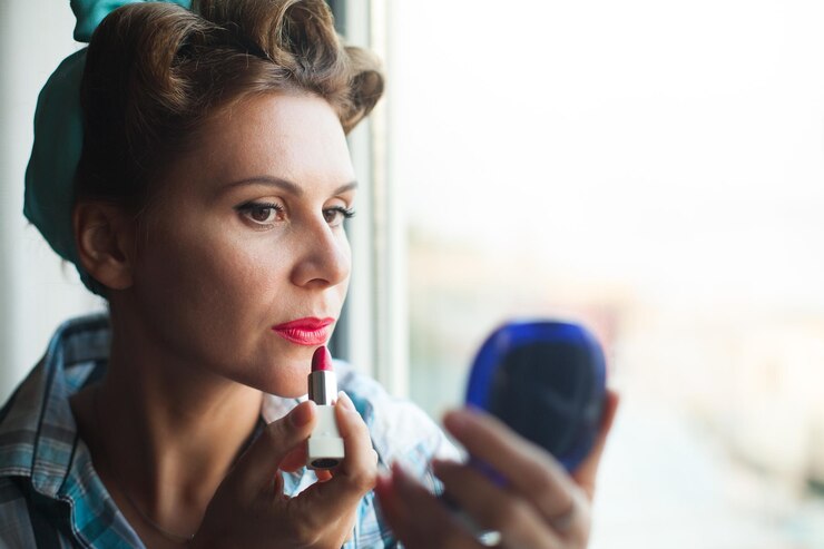 Foto mujer con peinado pinup cepillarse los labios y mirar en el espejo