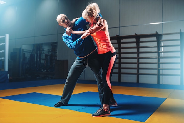 Mujer pelea con hombre en entrenamiento de autodefensa, entrenamiento de lucha en el gimnasio, arte marcial