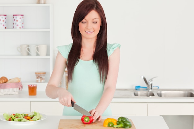 Mujer pelirroja atractiva cortar algunas verduras en la cocina