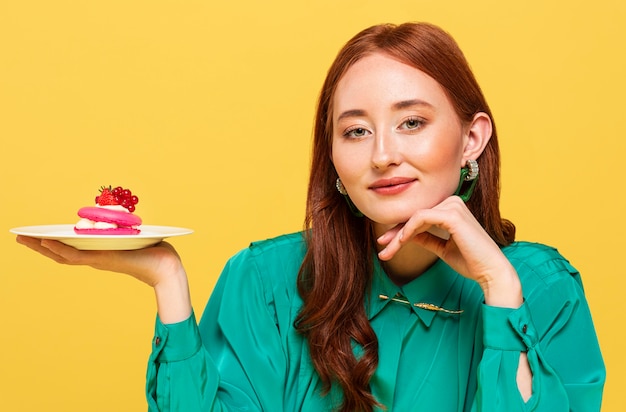 Foto mujer pelirroja en blusa verde mostrando un delicioso pastel