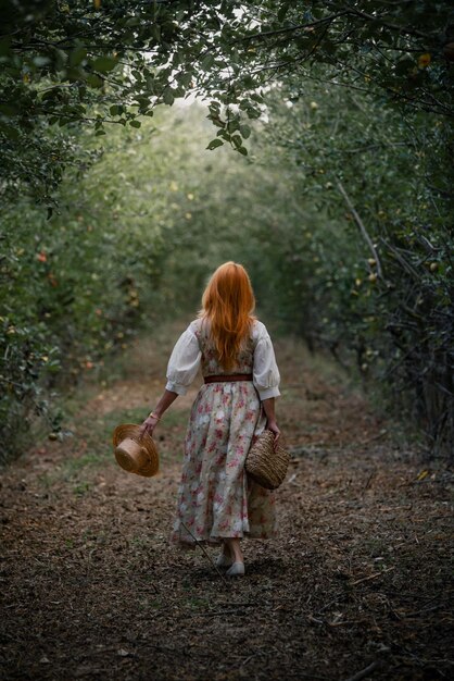 Mujer pelirroja caminando en un jardín de manzanos