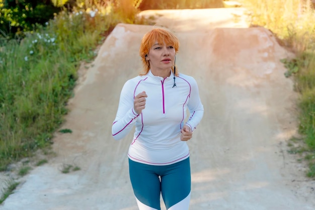 Una mujer pelirroja corriendo afuera en el parque contra un cielo azul