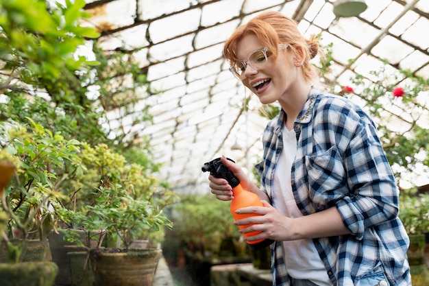 Mujer pelirroja cuidando sus plantas en invernadero