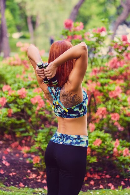 Foto mujer pelirroja deportiva relajándose en el parque de verano al aire libre.