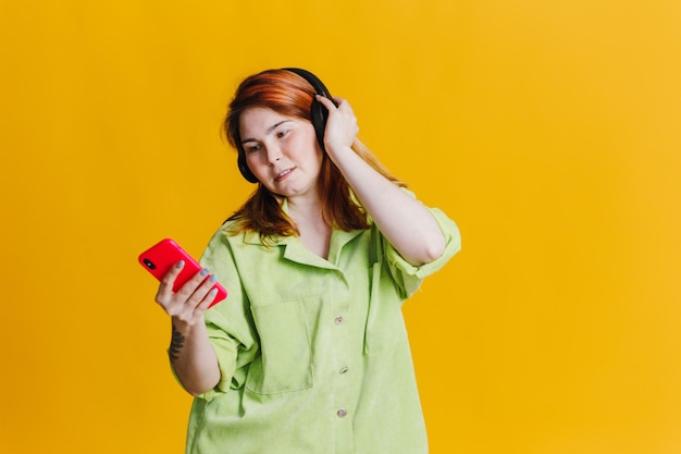 Mujer pelirroja escuchando música en su teléfono a través de auriculares