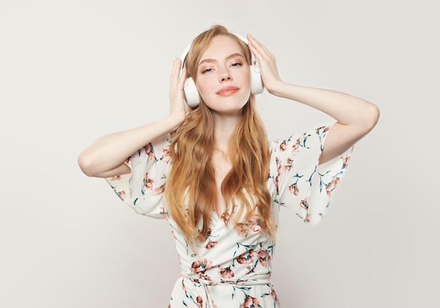 Mujer pelirroja feliz con auriculares en blanco