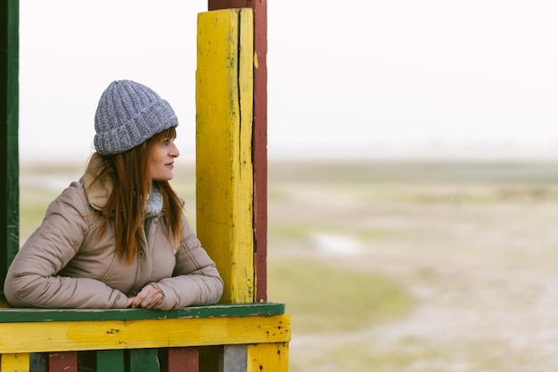 Mujer pelirroja con gorra de lana mira hacia el horizonte