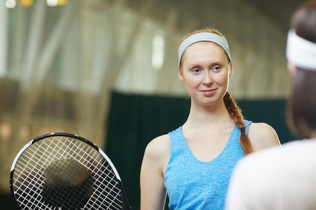 Mujer pelirroja hablando con compañero de tenis