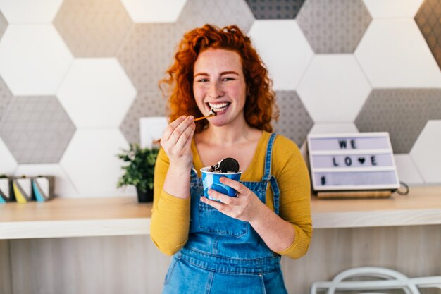 Mujer pelirroja hermosa y feliz disfrutando de comer delicioso helado artesanal.