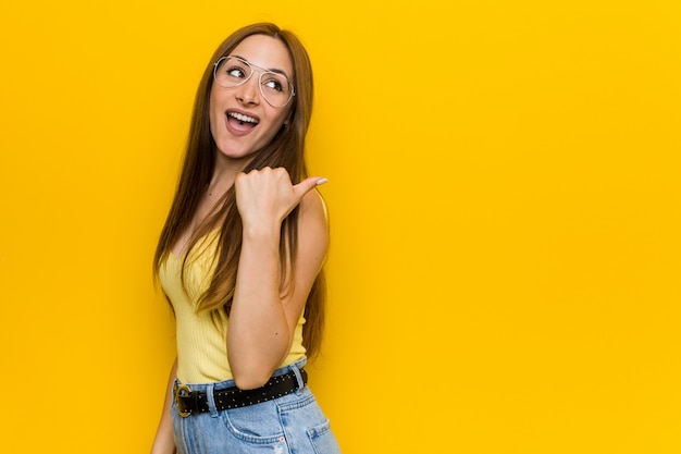 Mujer pelirroja jengibre joven con puntos sin pecas con el dedo pulgar lejos, riendo y despreocupada