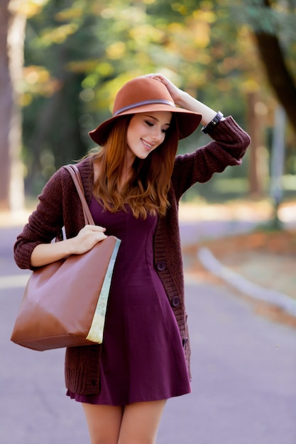 Foto mujer pelirroja joven con bolsa y sombrero