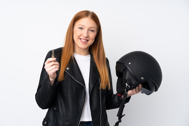 Mujer pelirroja joven con un casco de moto sobre pared blanca aislada