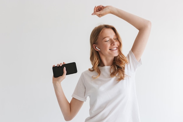 Mujer pelirroja joven linda emocional con auriculares.