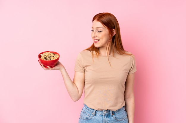 Mujer pelirroja joven que sostiene un tazón de cereales