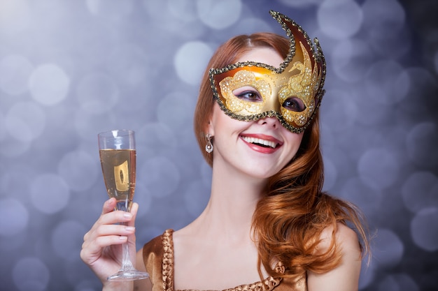 Mujer pelirroja en máscara con champagne