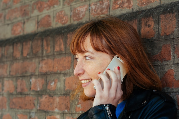 Mujer pelirroja mujer hablando por su teléfono móvil.