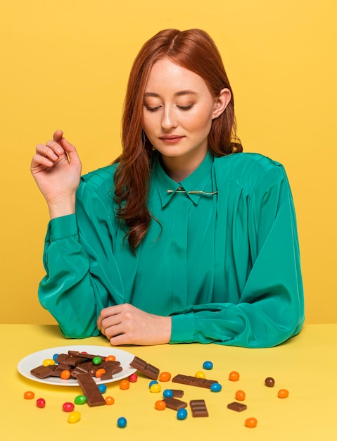 Foto mujer pelirroja posando con diferentes dulces