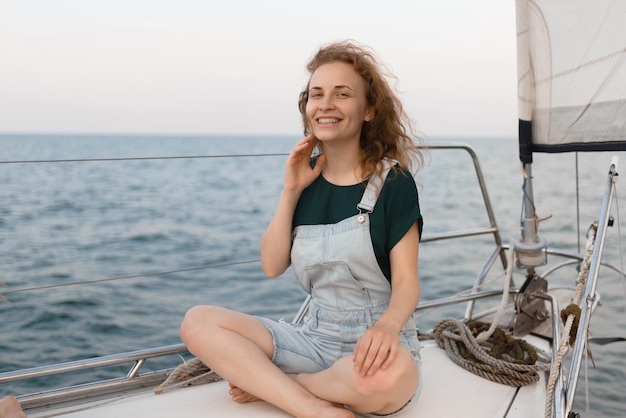 Una mujer pelirroja posando sentada en un yate en medio del mar durante el fin de semana de verano