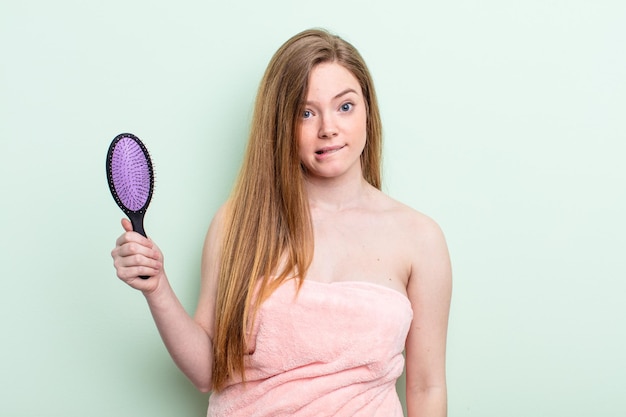 Mujer pelirroja que parece desconcertada y confundida. concepto de peine para el cabello