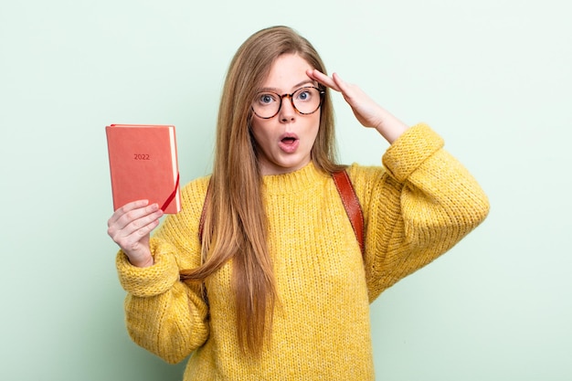 Mujer pelirroja que parece feliz, asombrado y sorprendido concepto de planificador