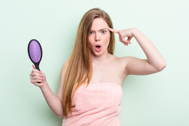 Mujer pelirroja que parece sorprendida al darse cuenta de una nueva idea de pensamiento o concepto de peine para el cabello