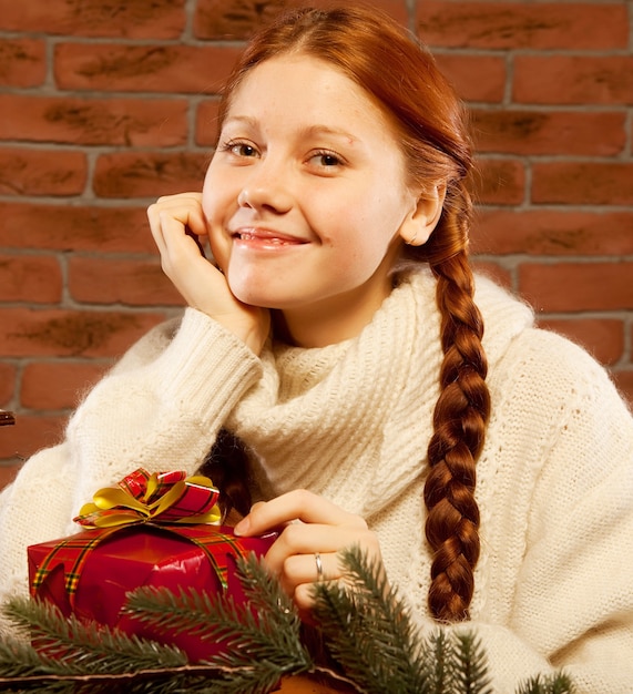 Mujer pelirroja con regalo de Navidad en el interior de una casa