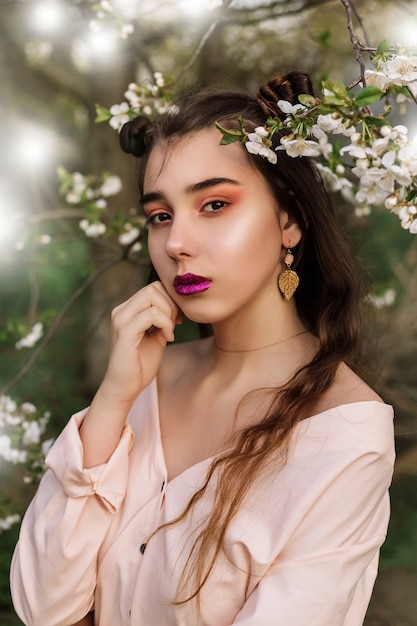 Mujer pelirroja de retrato de belleza en primavera en las ramas de un manzanos