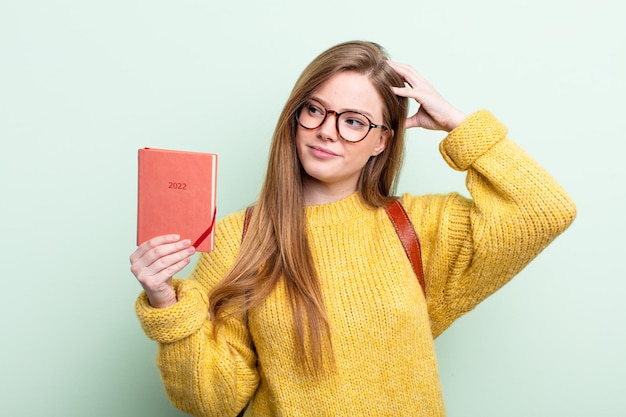 Mujer pelirroja sonriendo alegremente y soñando despierta o dudando del concepto de planificador