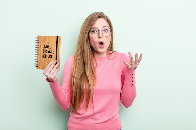 Mujer pelirroja sorprendida sorprendida y asombrada con un increíble concepto de reciclaje sorpresa