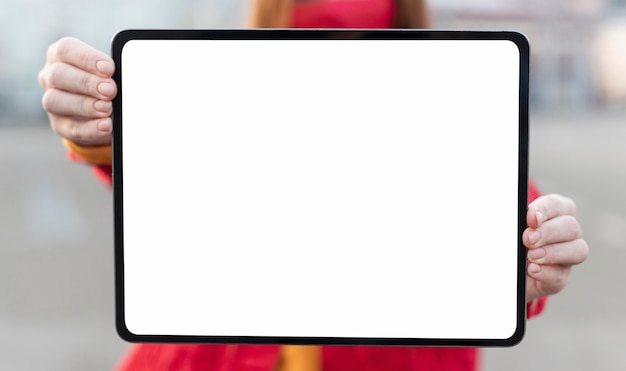 Mujer pelirroja sosteniendo una tableta en blanco