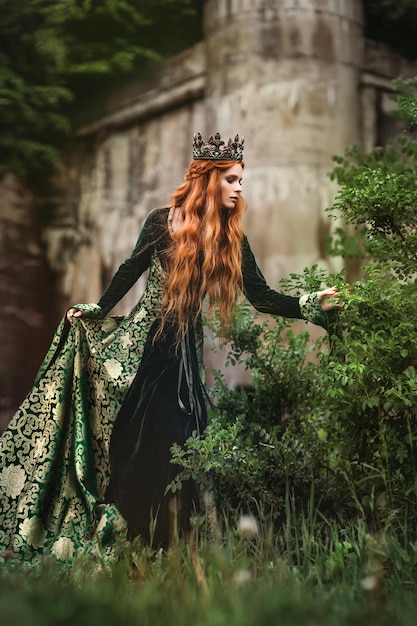 Mujer pelirroja con un vestido medieval verde cerca del castillo