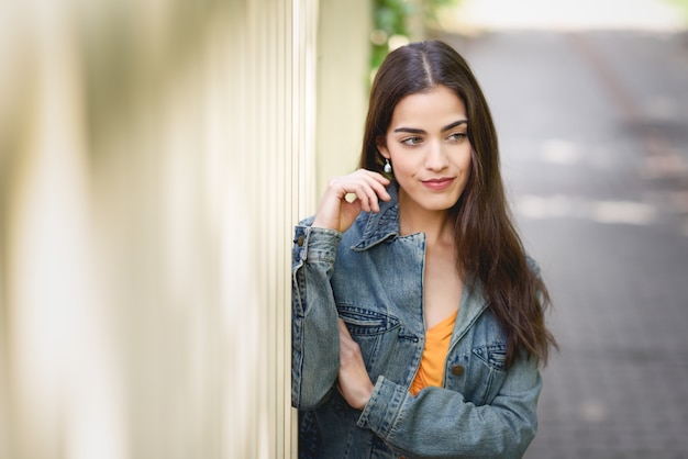 Mujer con el pelo agradable que desgasta la ropa ocasional en fondo urbano.