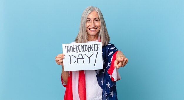 Mujer de pelo blanco de mediana edad apuntando a la cámara eligiéndote. concepto del día de la independencia