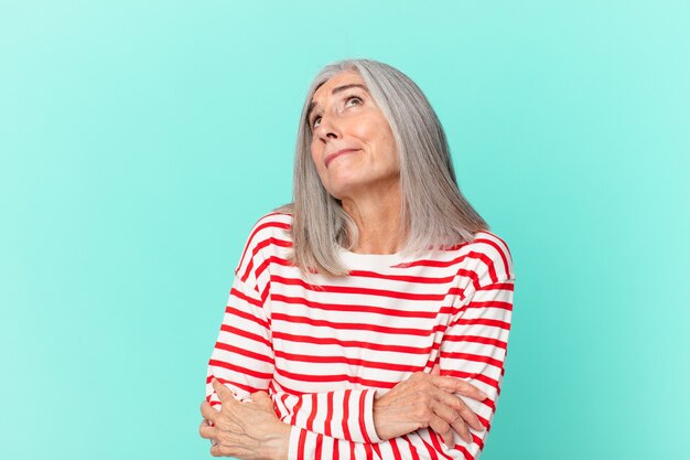 Mujer de pelo blanco de mediana edad encogiéndose de hombros, sintiéndose confundida e insegura