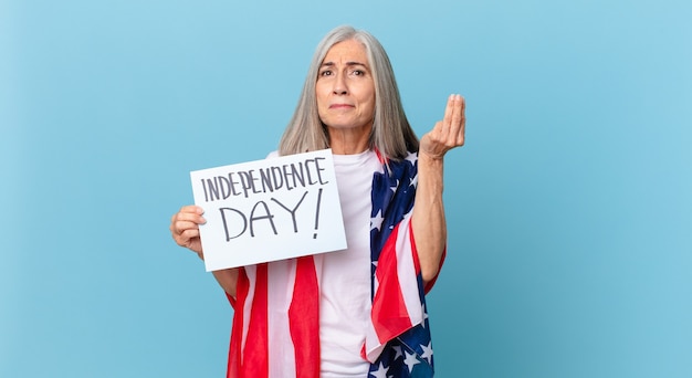 Mujer de pelo blanco de mediana edad haciendo capice o gesto de dinero, diciéndole que pague. concepto del día de la independencia