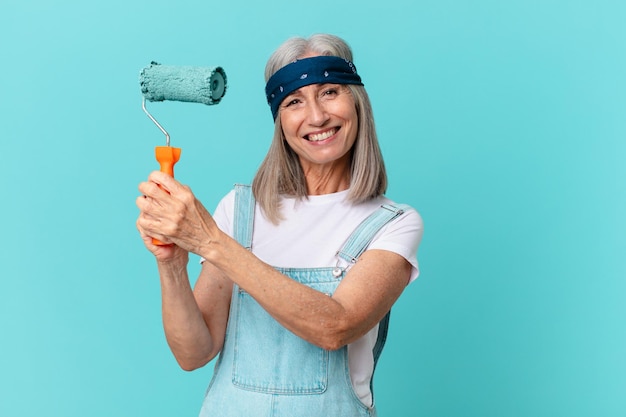 Mujer de pelo blanco de mediana edad pintando una pared