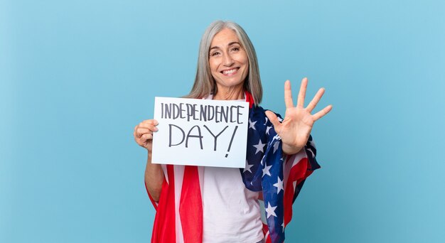 Mujer de pelo blanco de mediana edad sonriendo y mirando amigable, mostrando el número cinco. concepto del día de la independencia