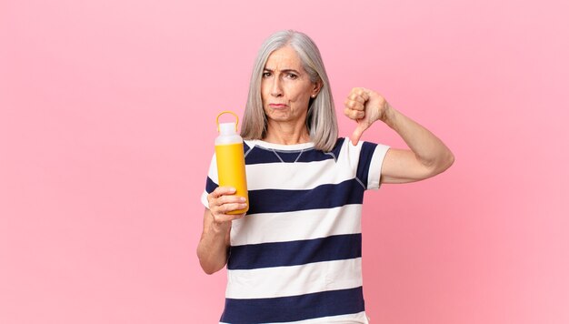 Mujer de pelo blanco de mediana edad sosteniendo un termo de café