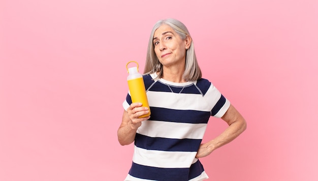 Mujer de pelo blanco de mediana edad sosteniendo un termo de café