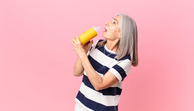 Mujer de pelo blanco de mediana edad sosteniendo un termo de café