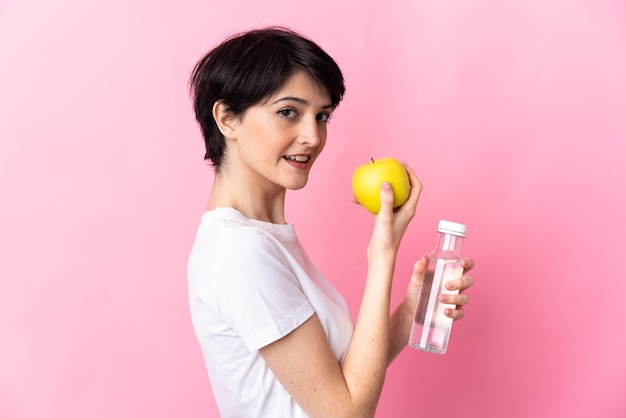 Mujer con pelo corto encima con una manzana y con una botella de agua