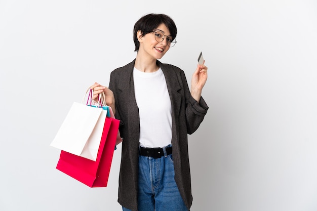 Mujer con pelo corto sobre sosteniendo bolsas de compras aisladas y una tarjeta de crédito