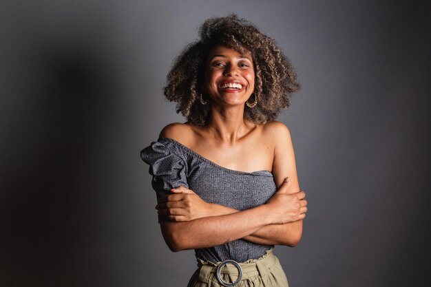 Una mujer de pelo corto sonríe y sonríe con un top gris.