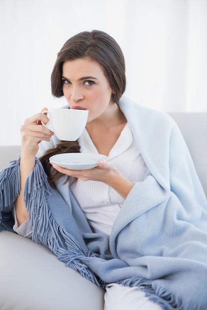 Mujer de pelo marrón casual tranquila en pijama blanco tomando café