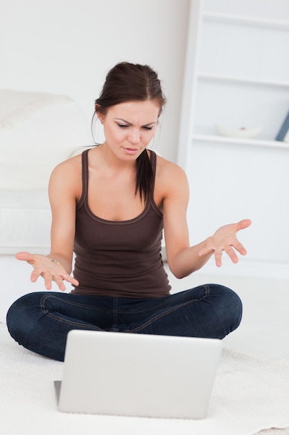 Mujer de pelo oscuro enojado usando su computadora portátil