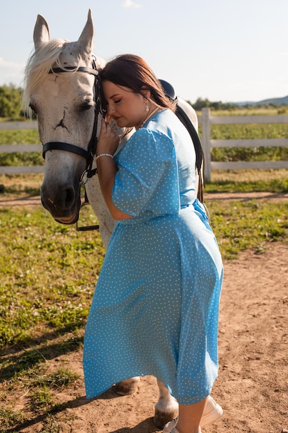 La mujer con el pelo rizado se acurruca junto a su caballo.