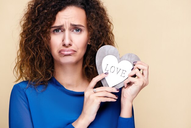 Mujer de pelo rizado atractivo con corazón de madera