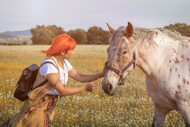 Mujer con pelo rojo cerca de un caballo