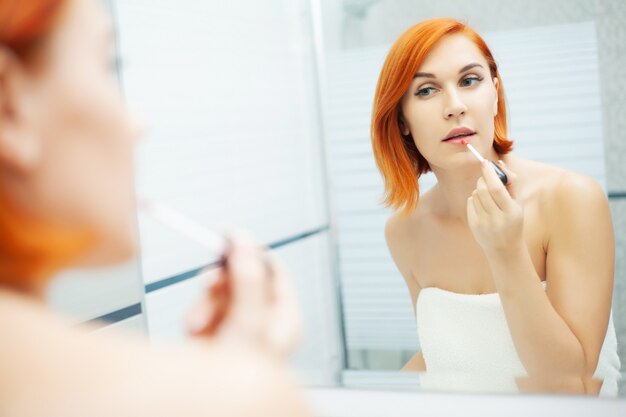 Mujer con el pelo rojo haciendo su maquillaje